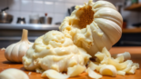 High-quality garlic paste being prepared with fresh garlic cloves on a wooden table, showcasing